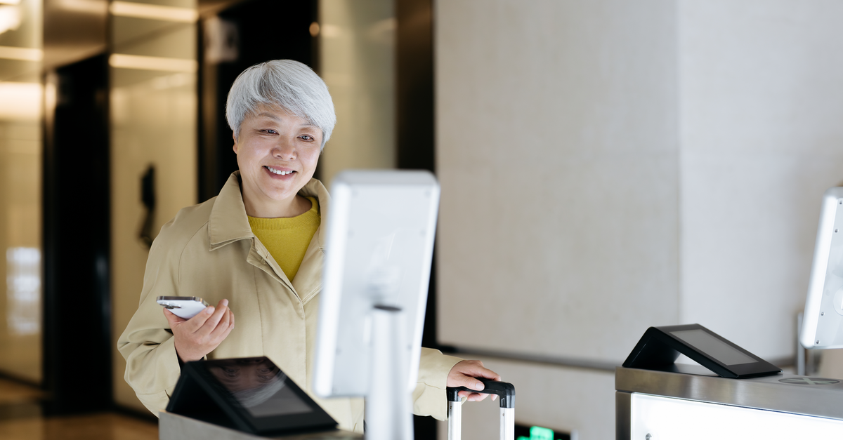 A woman passing through a gate at airport or similar using facial recognition biometrics 