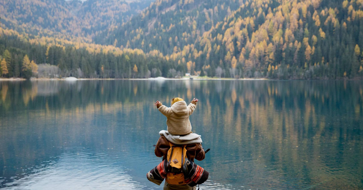 Back view of backpackers in mountains with lake