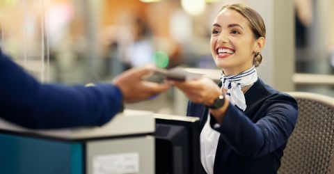 Smiling airport staff supporting traveler at the airport counter